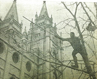 Historic photo of Behunin worker stringing lights at Temple Square