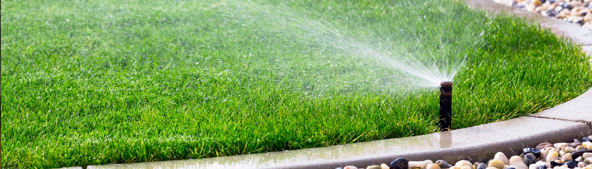 Sprinkler system watering a green lawn